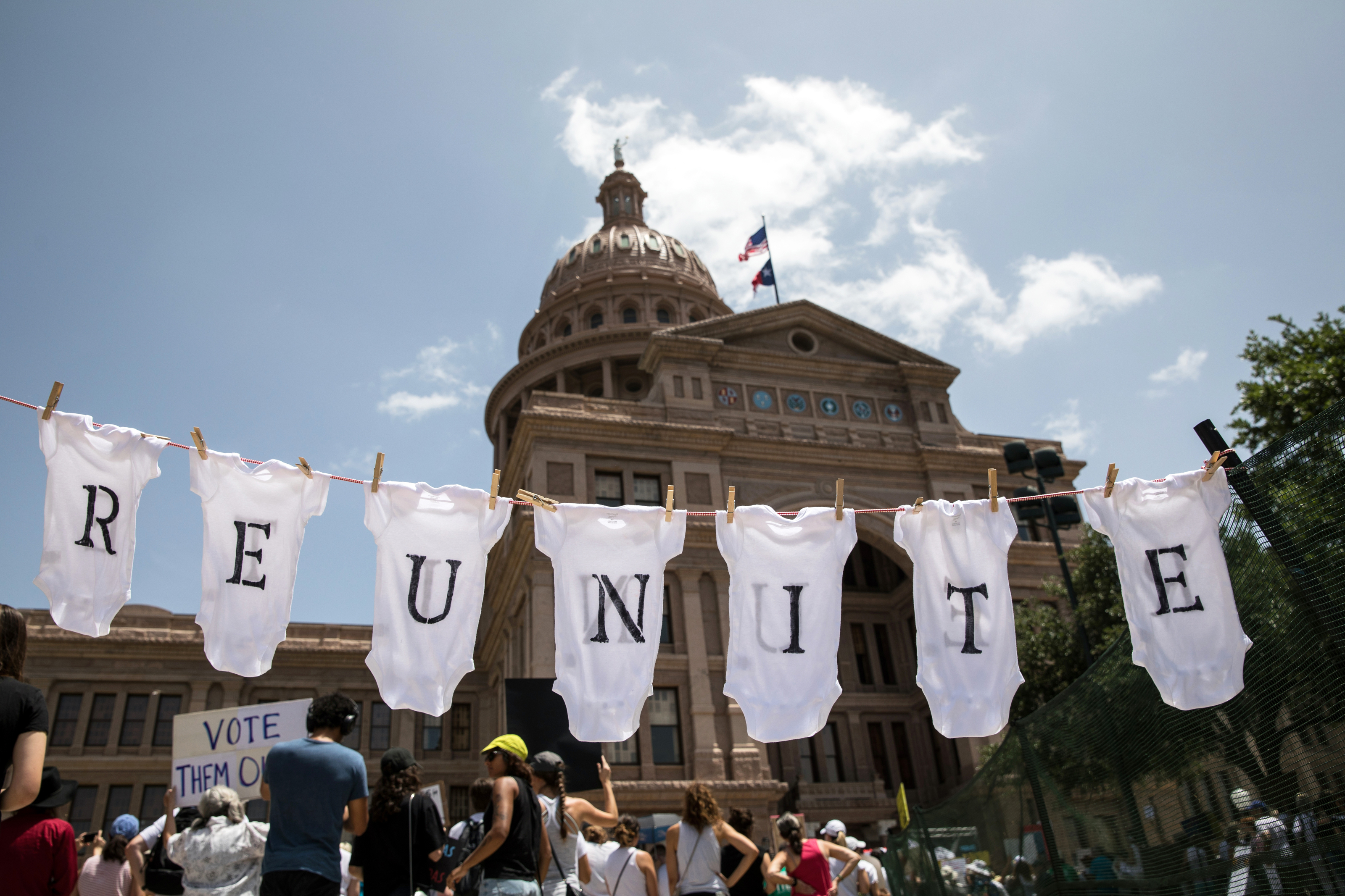 AUSTIN, TX - JUNE 30: A demonstrator uses baby clothes to spell out the word "reunite" during a rally against the Trump administration's immigration policies outside the Texas Capitol in Austin, Texas, on June 30, 2018. Demonstrations are being held in cities across the U.S. Saturday to call for the reunification of separated families and to protest the detention of children and families seeking asylum at the border. (Photo by Tamir Kalifa/Getty Images)